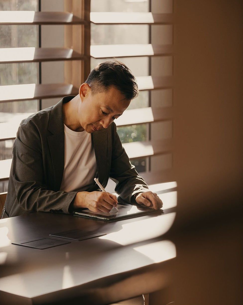 A man writing on a tablet at a desk.